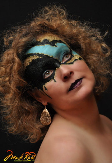 curly haired woman wiht a blue, gold, and black mask on her upper face